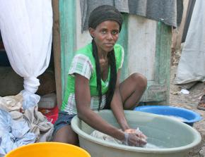 A woman displaced by January's earthquake washes clothes outside a makeshift shelter in Port-au-Prince